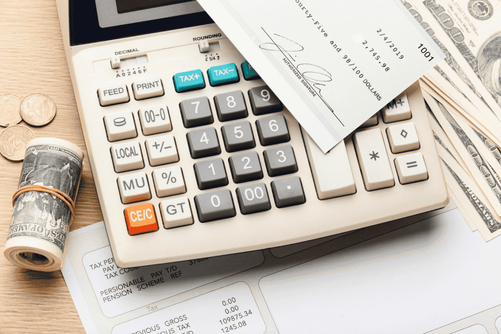 A calculator with a cheque and cash on a desk