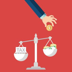 Hand dropping coin onto balance scale weighing tax documents against money, illustrating tax planning and financial decision-making.