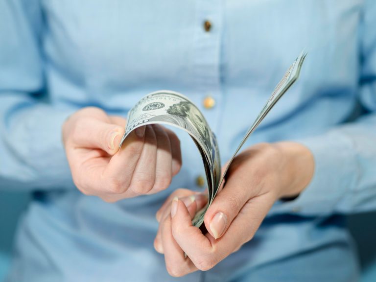 Person counting cash, symbolising income, payroll, and salary sacrifice money management.