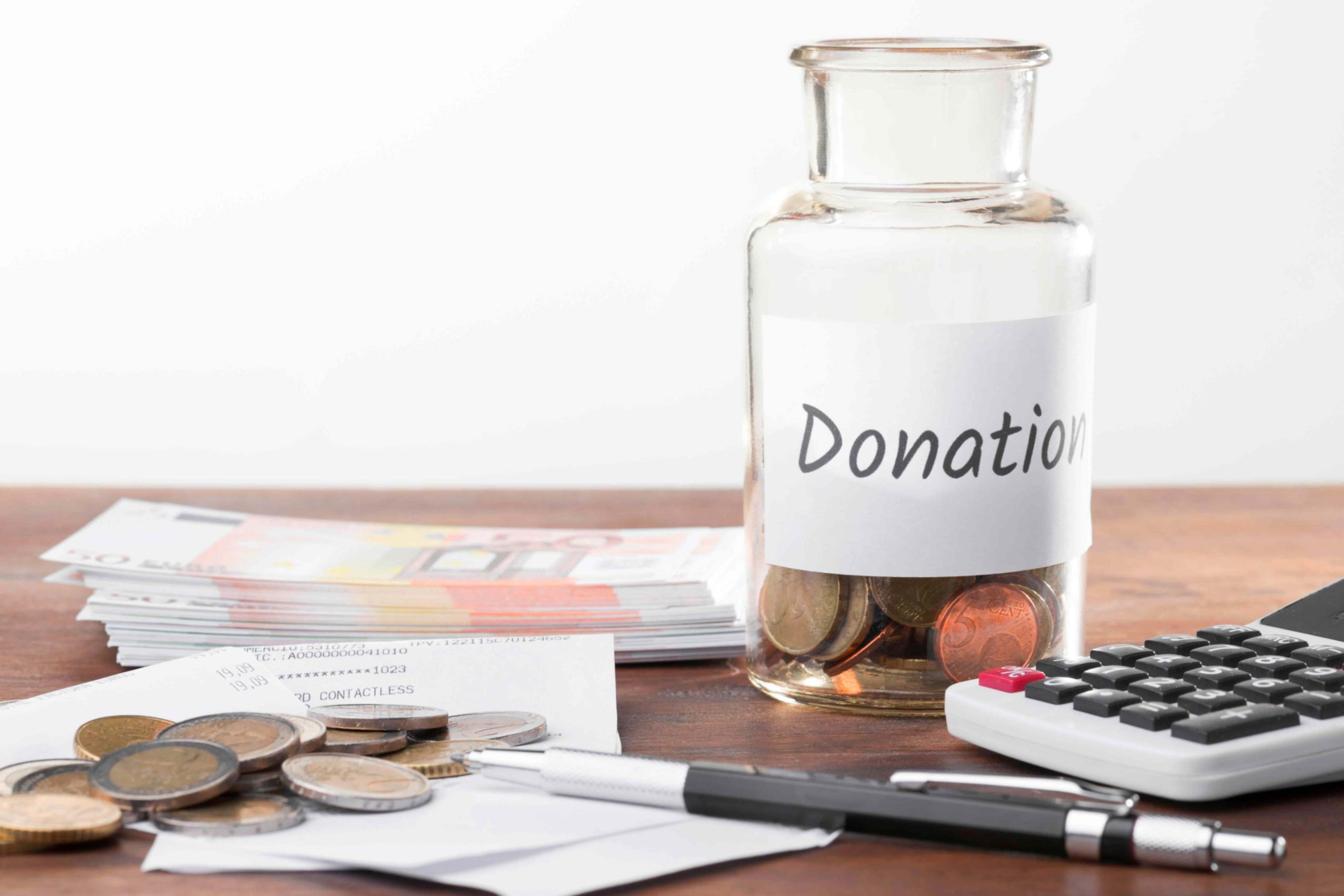 Donation jar, cash and calculator on a table
