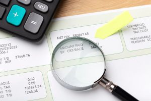 payroll document and magnifying glass on a table 