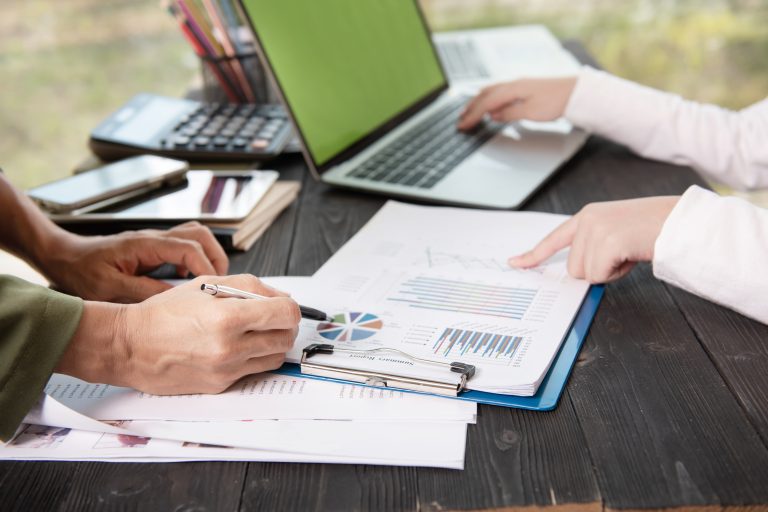 Two people sitting at a dark wooden desk collaborating on data analysis